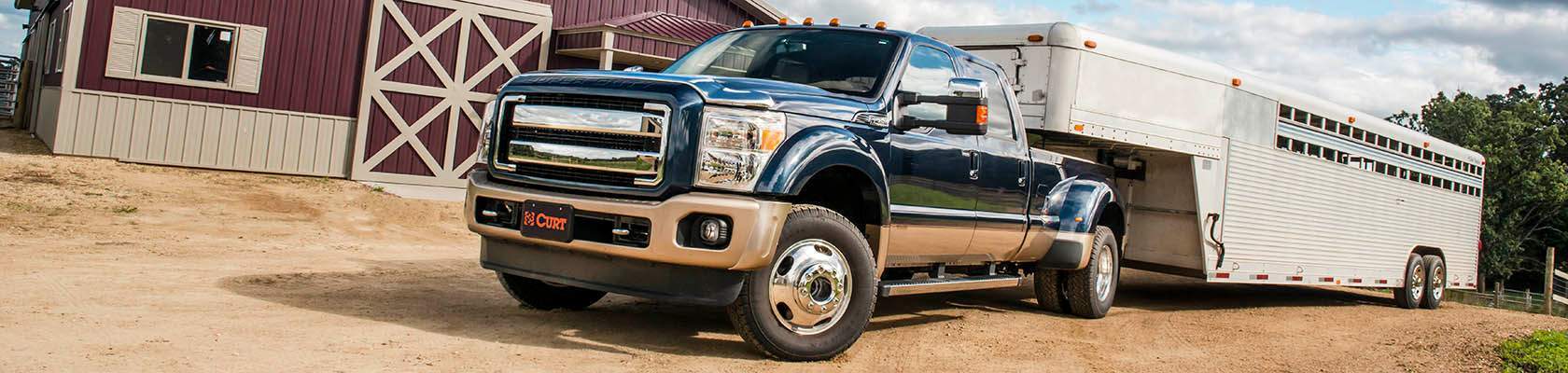 Heavy-duty commercial truck utilizing an underbed CURT gooseneck hitch system to safely tow a loaded flatbed trailer